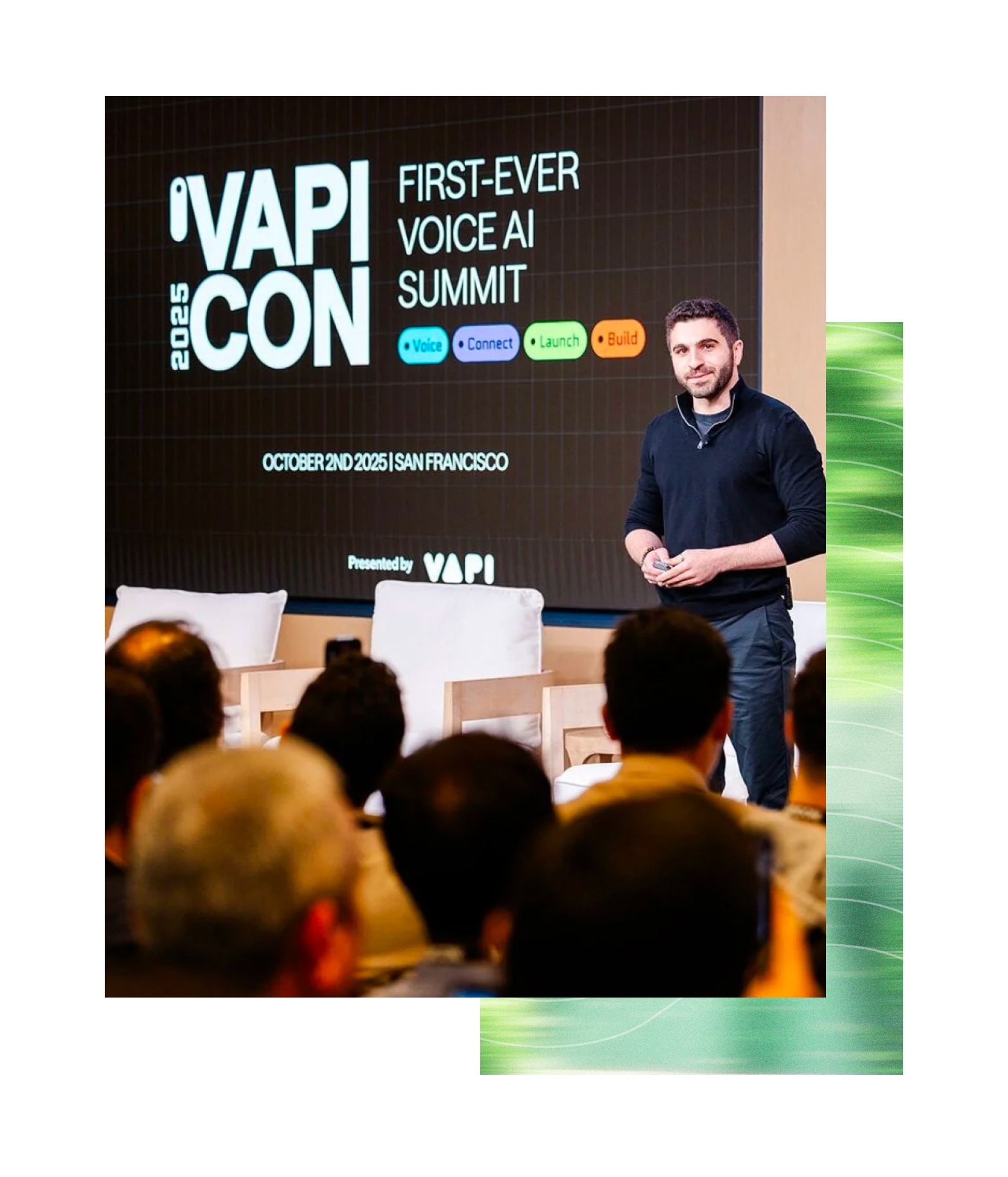 A man speaking at the 2025 VAPI CON First-Ever Voice AI Summit in San Francisco, October 2nd, 2025, with a large screen behind him showing the event title and colorful icons for Voice, Connect, Launch, and Build.