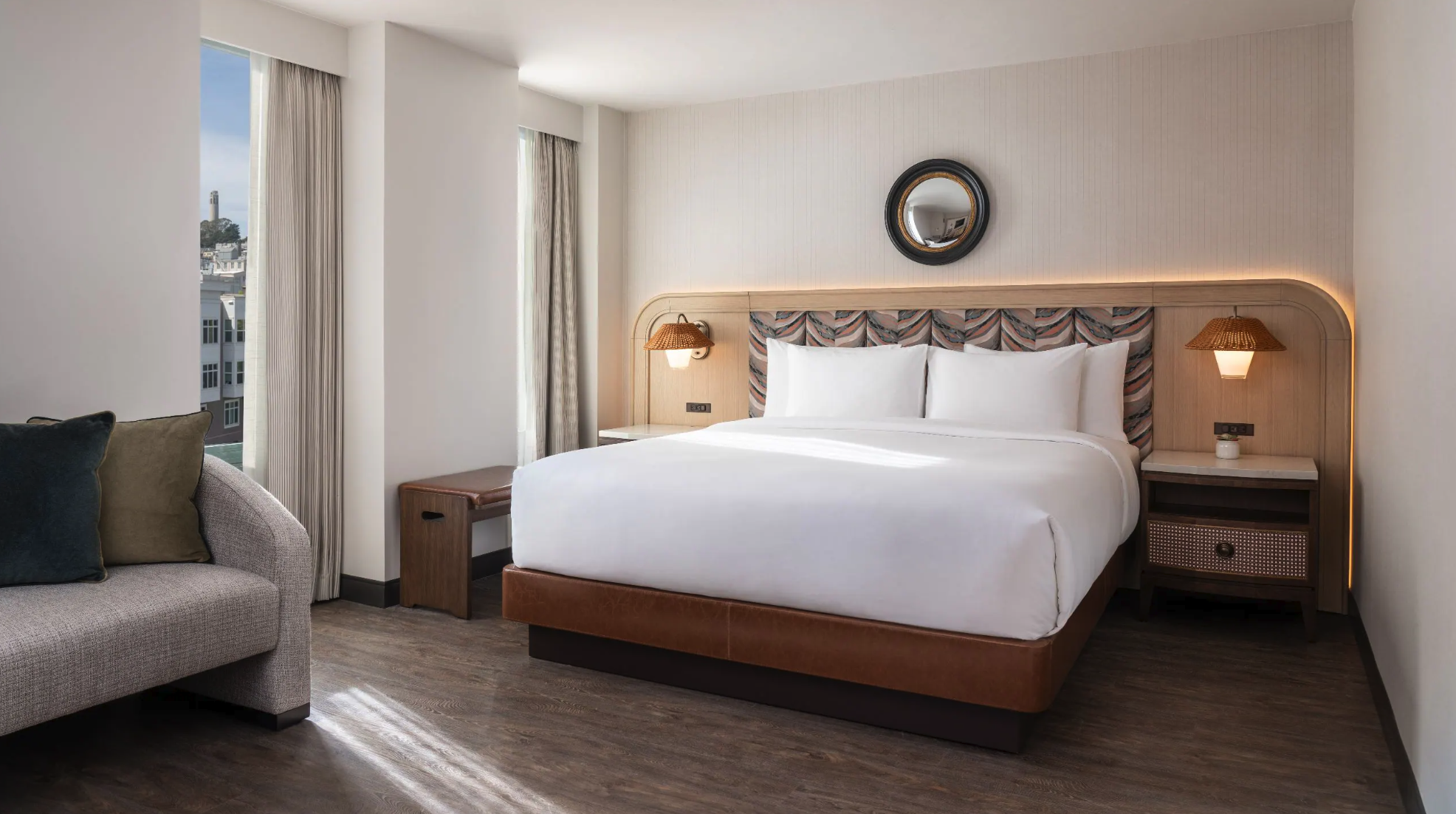 Modern hotel room with a cozy bed, nightstands, and a window with city views.